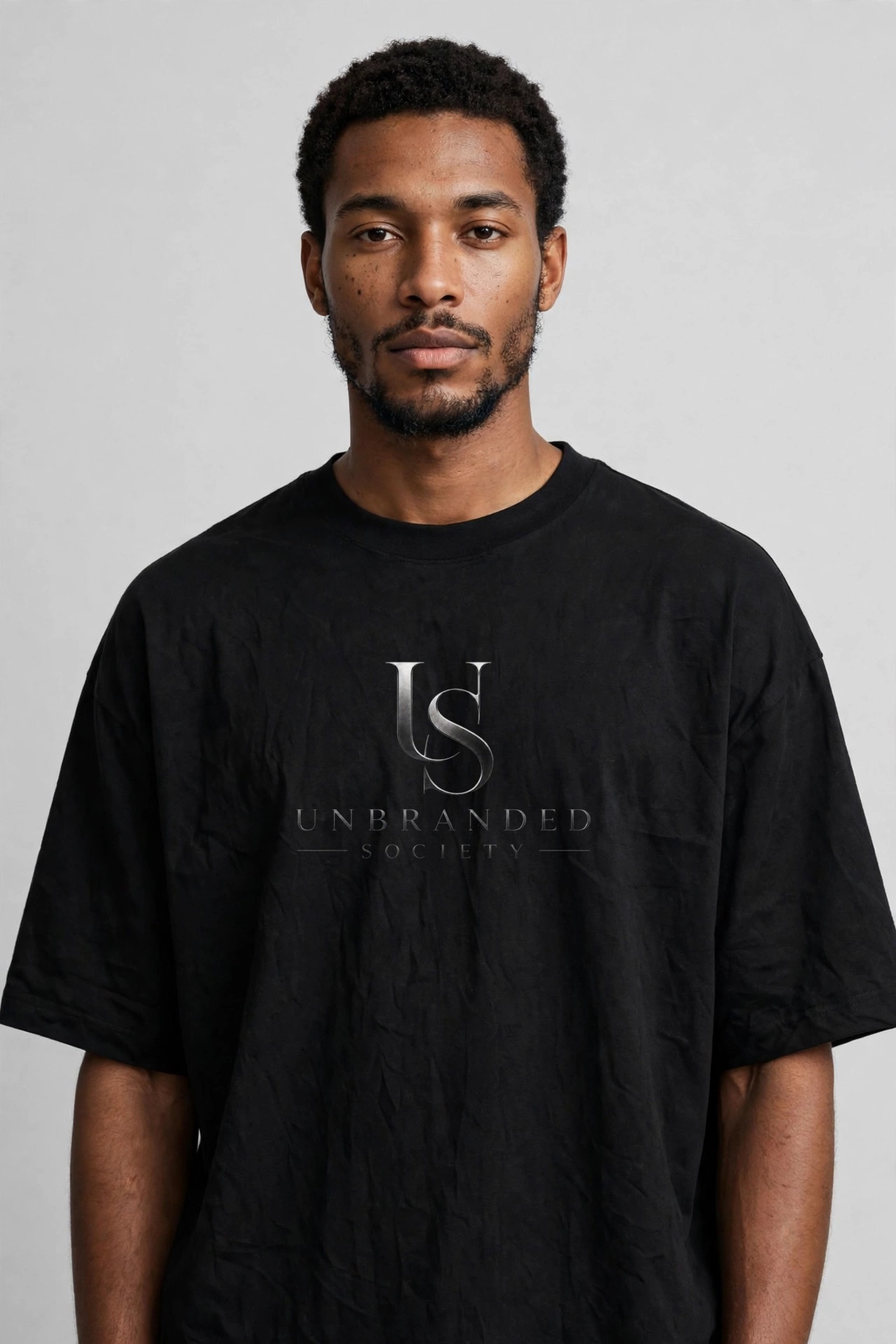 Oversized T-shirt, front view, with the silver Unbranded Society logo on the chest.
